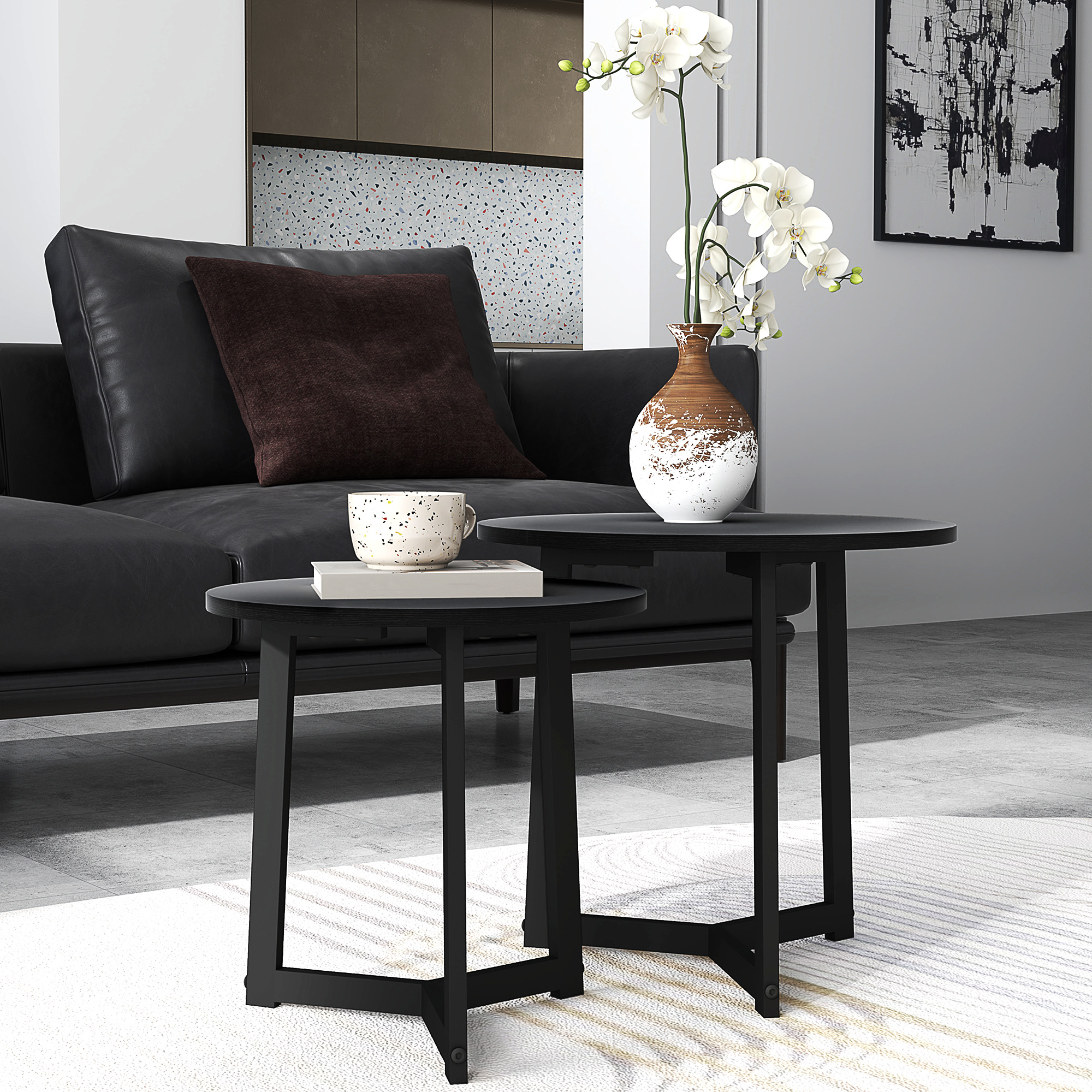 Zwei schwarze runde Tische, einer mit Buch und Tasse, der andere mit Vase und Blume, in einem Wohnzimmer.