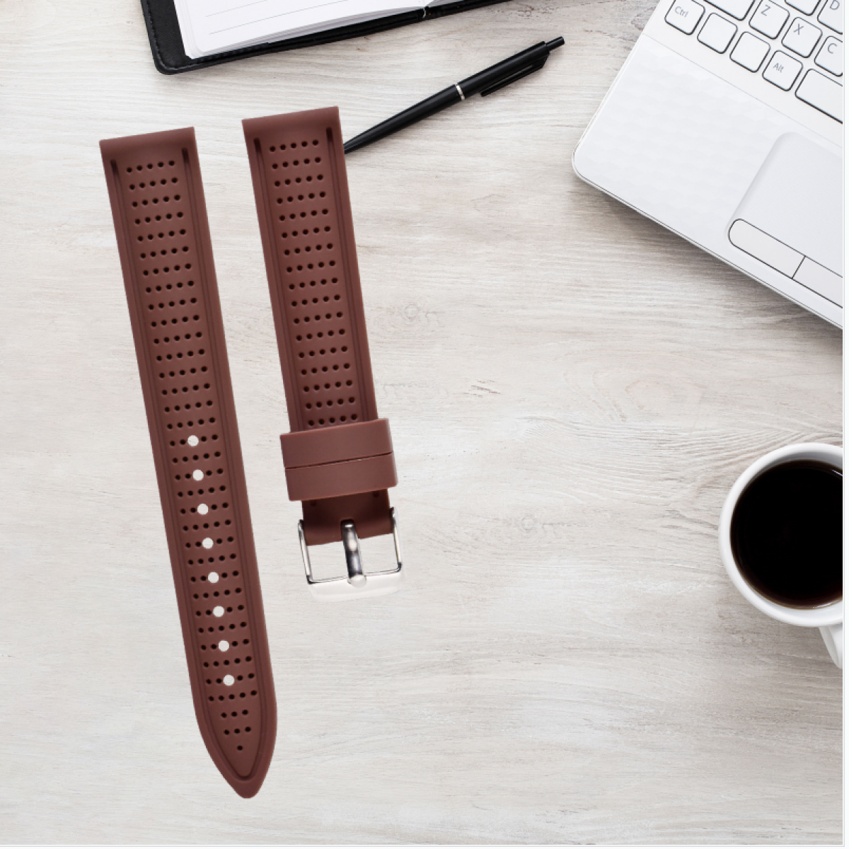 Cinturini marroni su un tavolo di legno con laptop, penna e caffè.