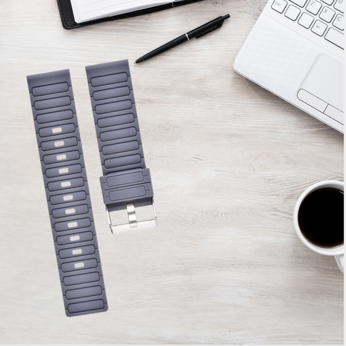 Graue Armbänder auf einem Holzschreibtisch mit Stift, Notizbuch und Kaffeetasse.