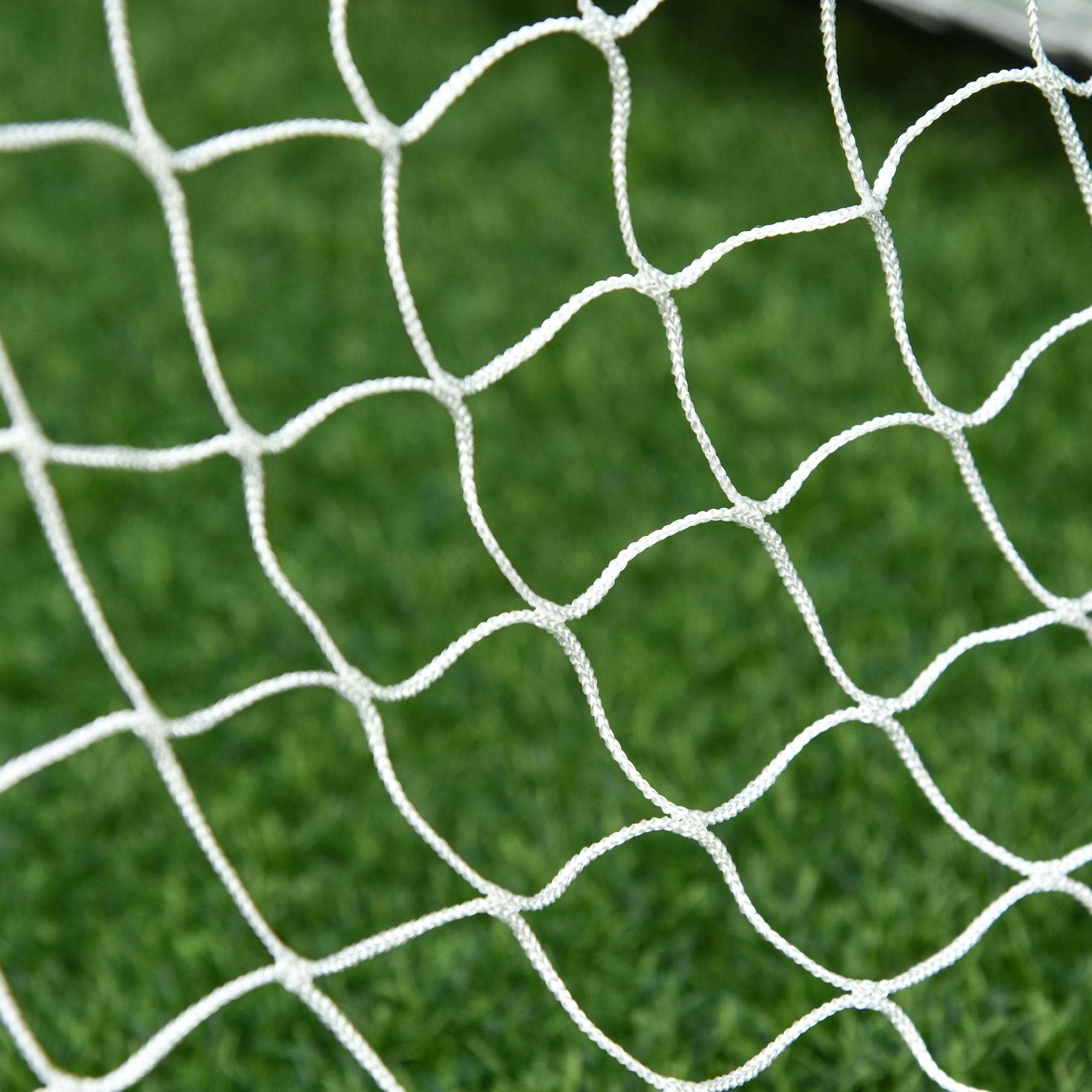 Nahaufnahme eines weißen Fußballnetzes mit grünem Gras im Hintergrund.
