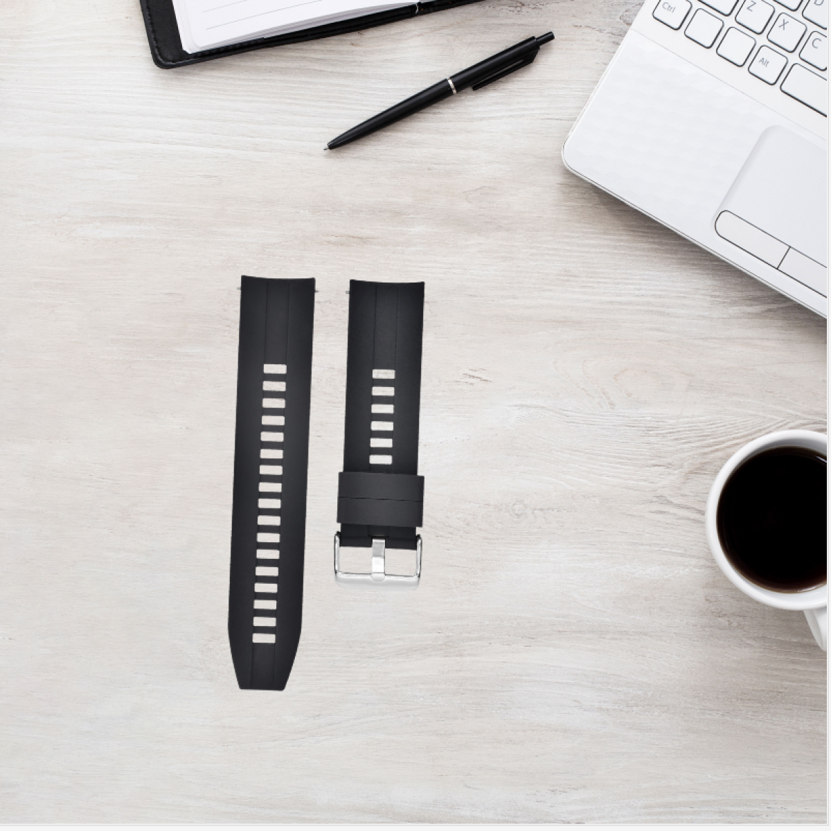 Cinturini neri per orologi, uno con fibbia, su una superficie di legno chiaro accanto a un laptop e una tazza di caffè.
