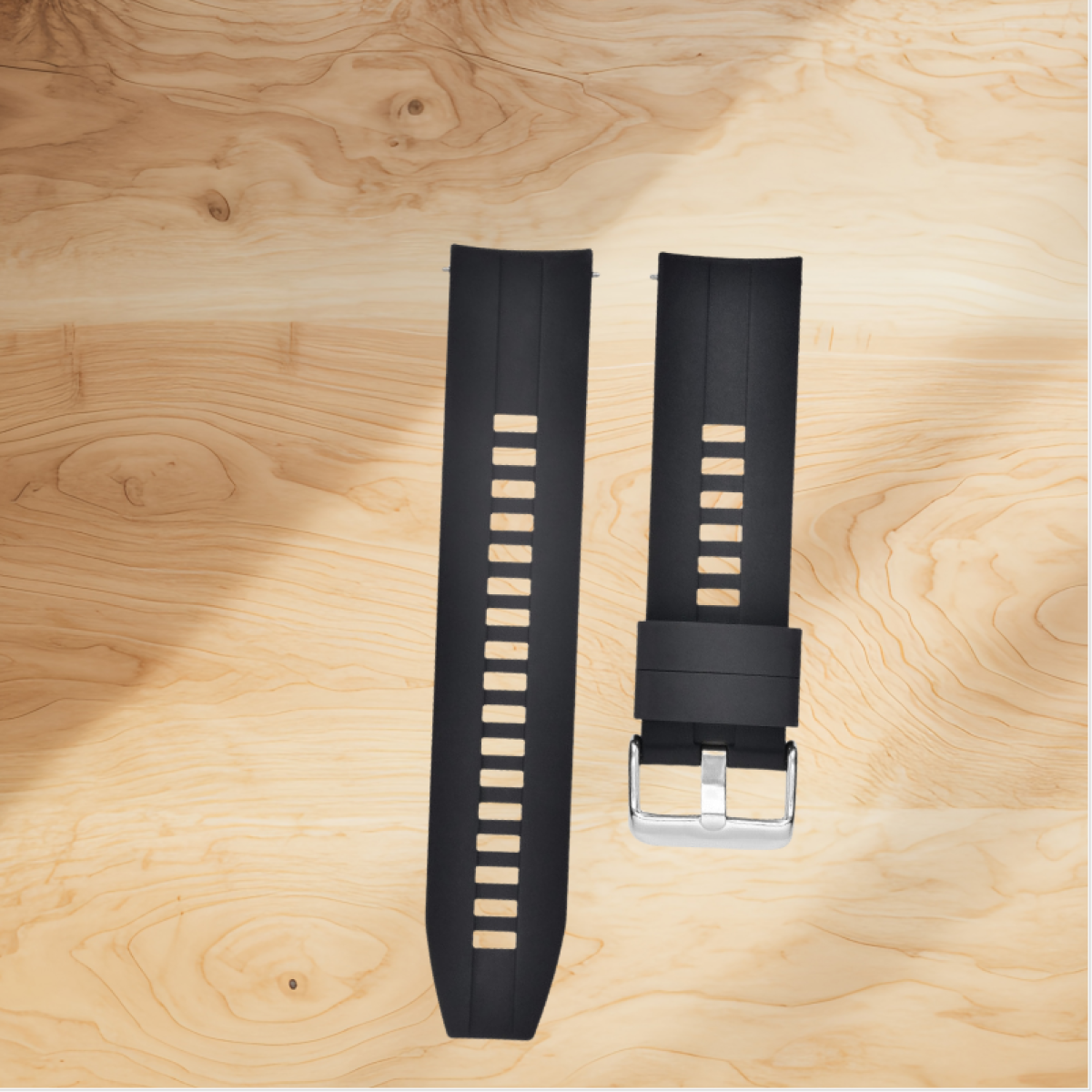 Due cinturini neri per orologi con fessure bianche su una superficie in legno, uno con fibbia argentata.