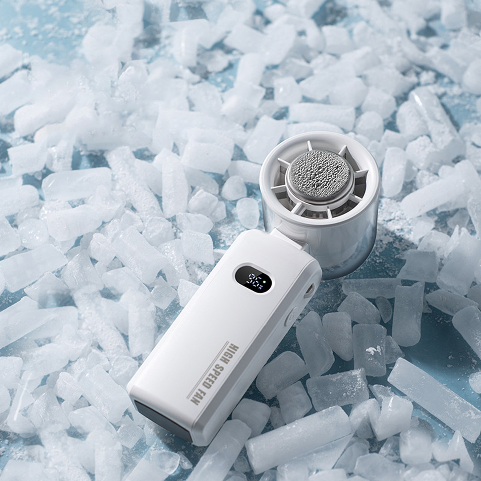 Ein weißer tragbarer Ventilator liegt auf einem Haufen Eiswürfel. Der Ventilator hat eine Digitalanzeige.