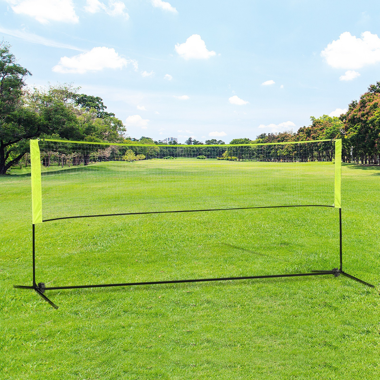 Ein Badmintonnetz auf einem grasbewachsenen Feld aufgebaut. Der Himmel ist blau, und Bäume sind im Hintergrund.