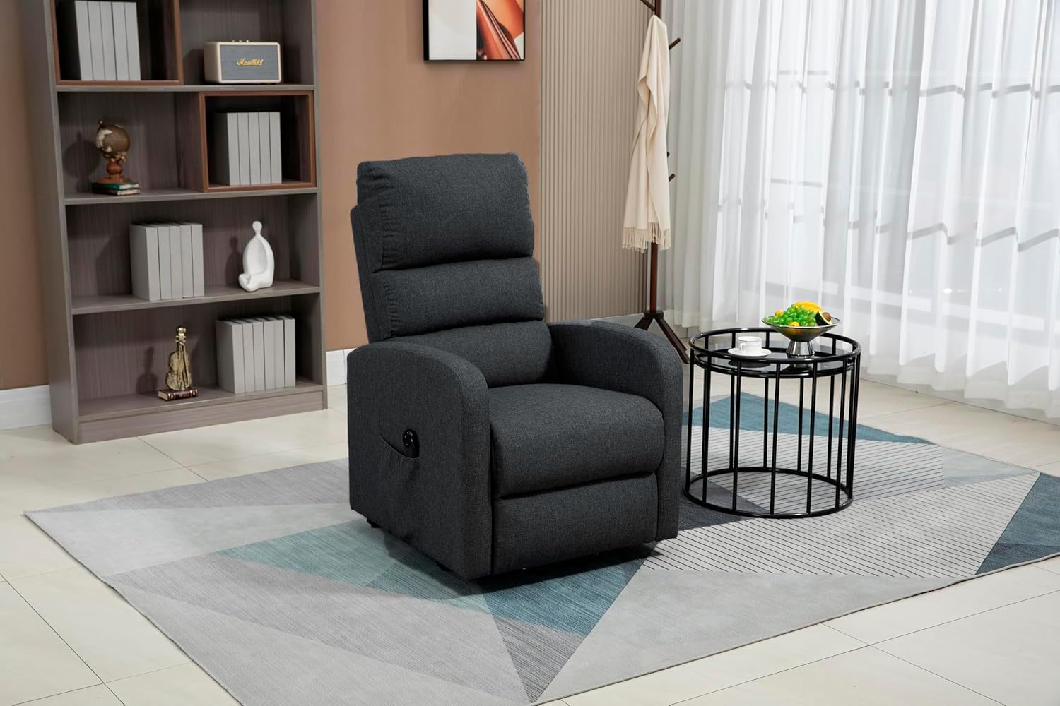 Sillón reclinable gris oscuro en un salón, cerca de una estantería y una alfombra.