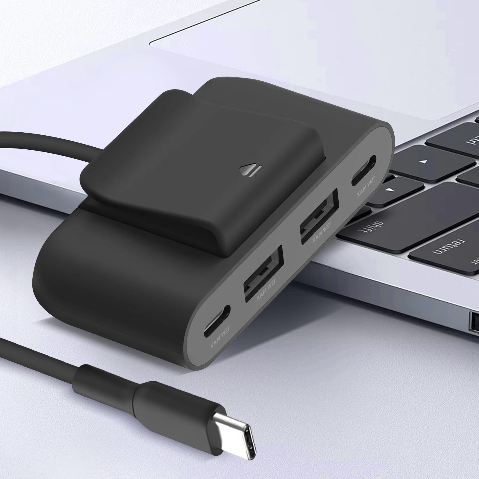 Hub USB nero su una tastiera del laptop. Cavo nero collegato. Sfondo bianco.