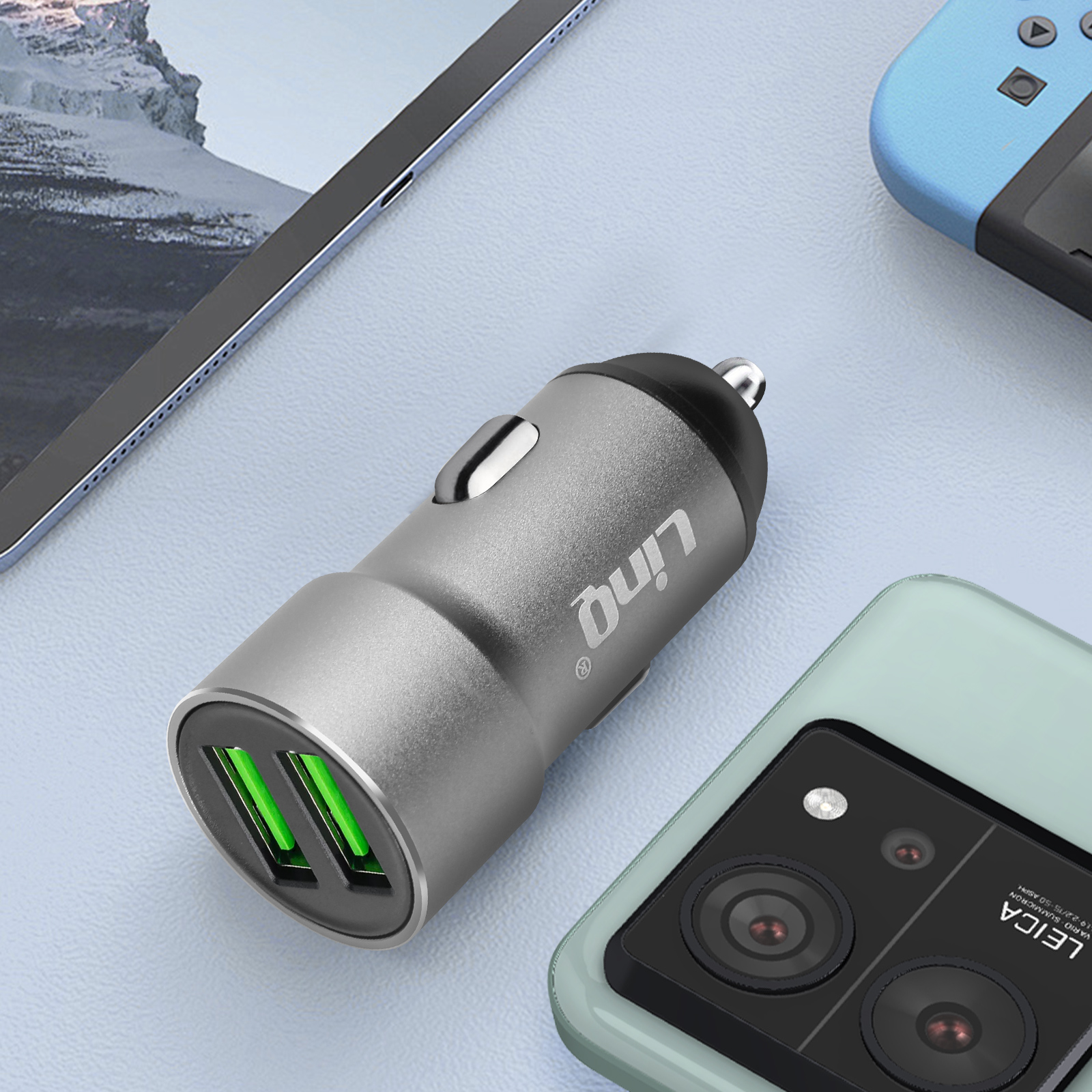 Caricabatterie per auto grigio che carica un telefono, accanto a tablet e console.