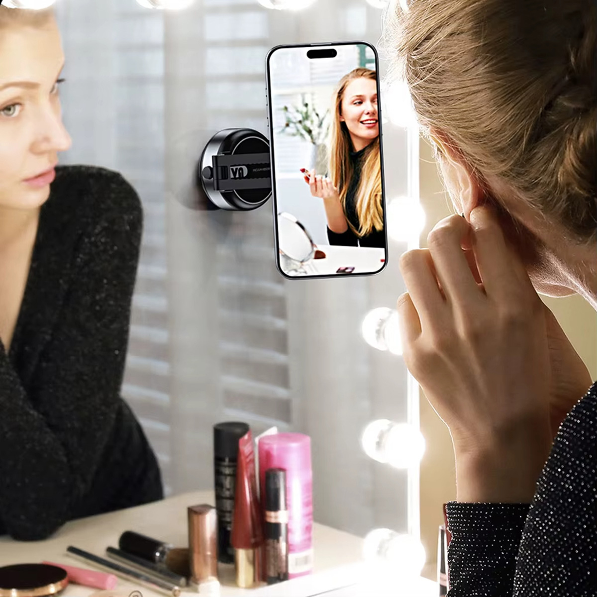 Mujer mirando un espejo. Un teléfono está adjunto al espejo que muestra un video de otra mujer.