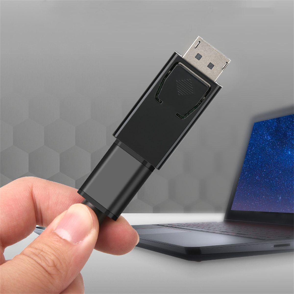Hand hält einen schwarzen DisplayPort-zu-HDMI-Adapter, Laptop im Hintergrund.