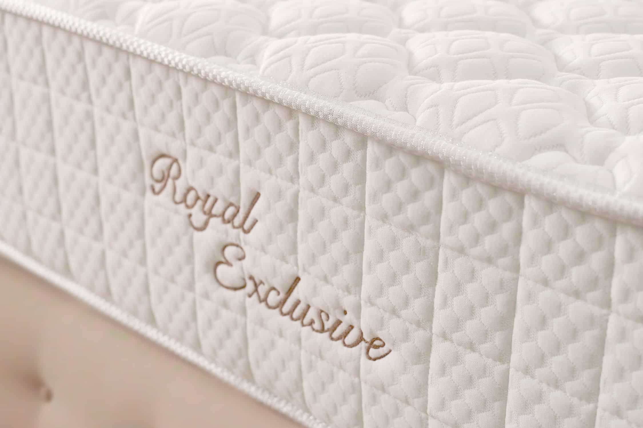 Primer plano de un colchón blanco con texto bordado: "Royal Exclusive."