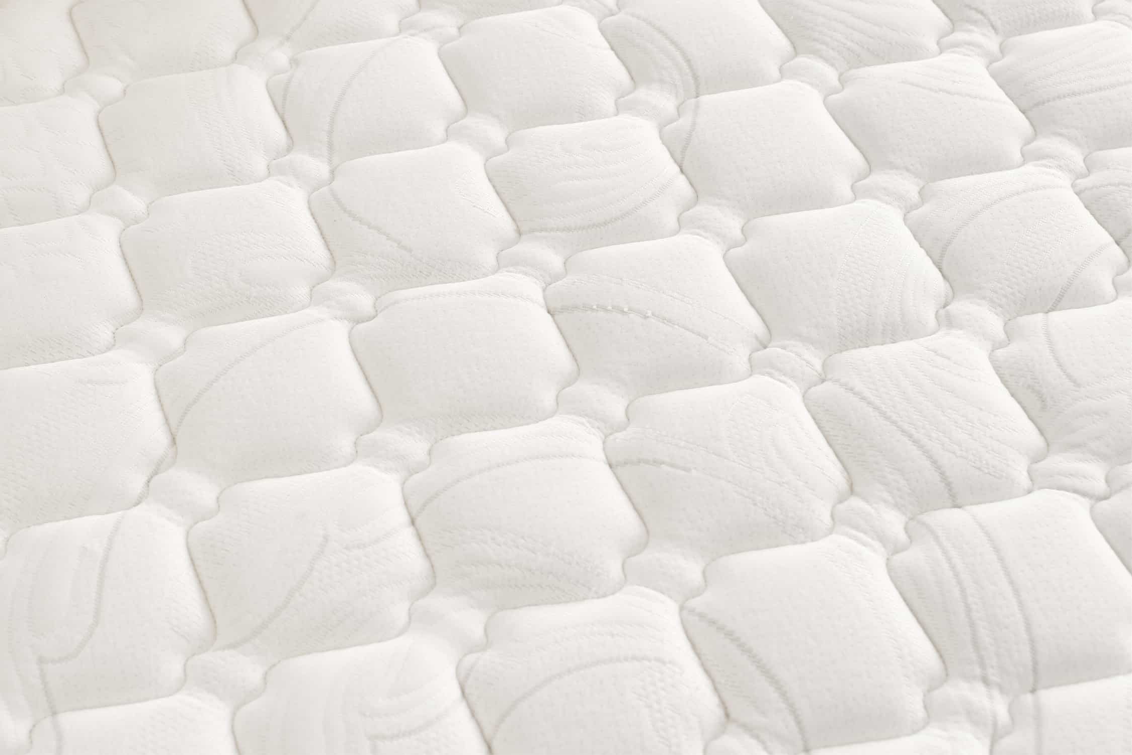 Primer plano de un colchón blanco con un patrón cuadrado acolchado.