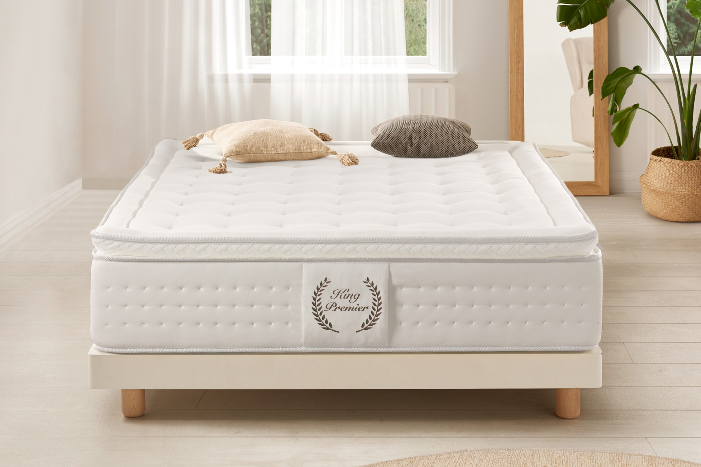 Colchón blanco con almohadas en una cama. Mesa y lámpara cerca. Una habitación luminosa.
