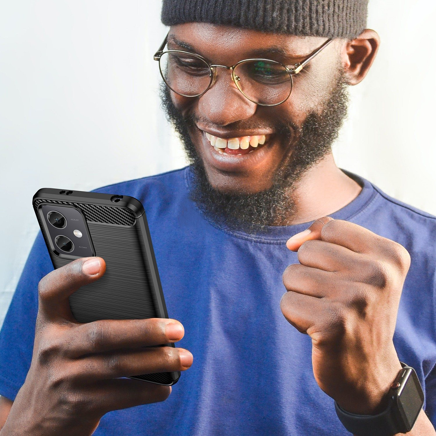 Un hombre sonríe y sostiene un teléfono con una funda negra. La funda tiene una parte trasera texturizada.