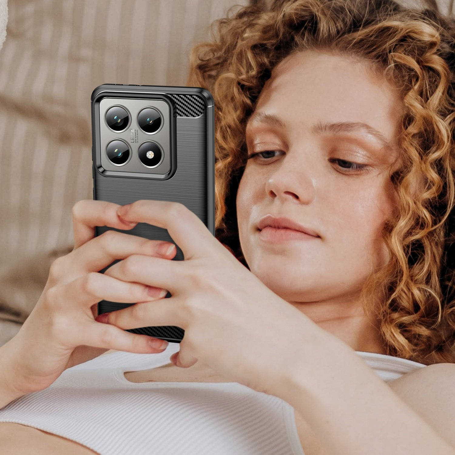 Mujer sosteniendo teléfono negro con funda, enfocada en el teléfono.