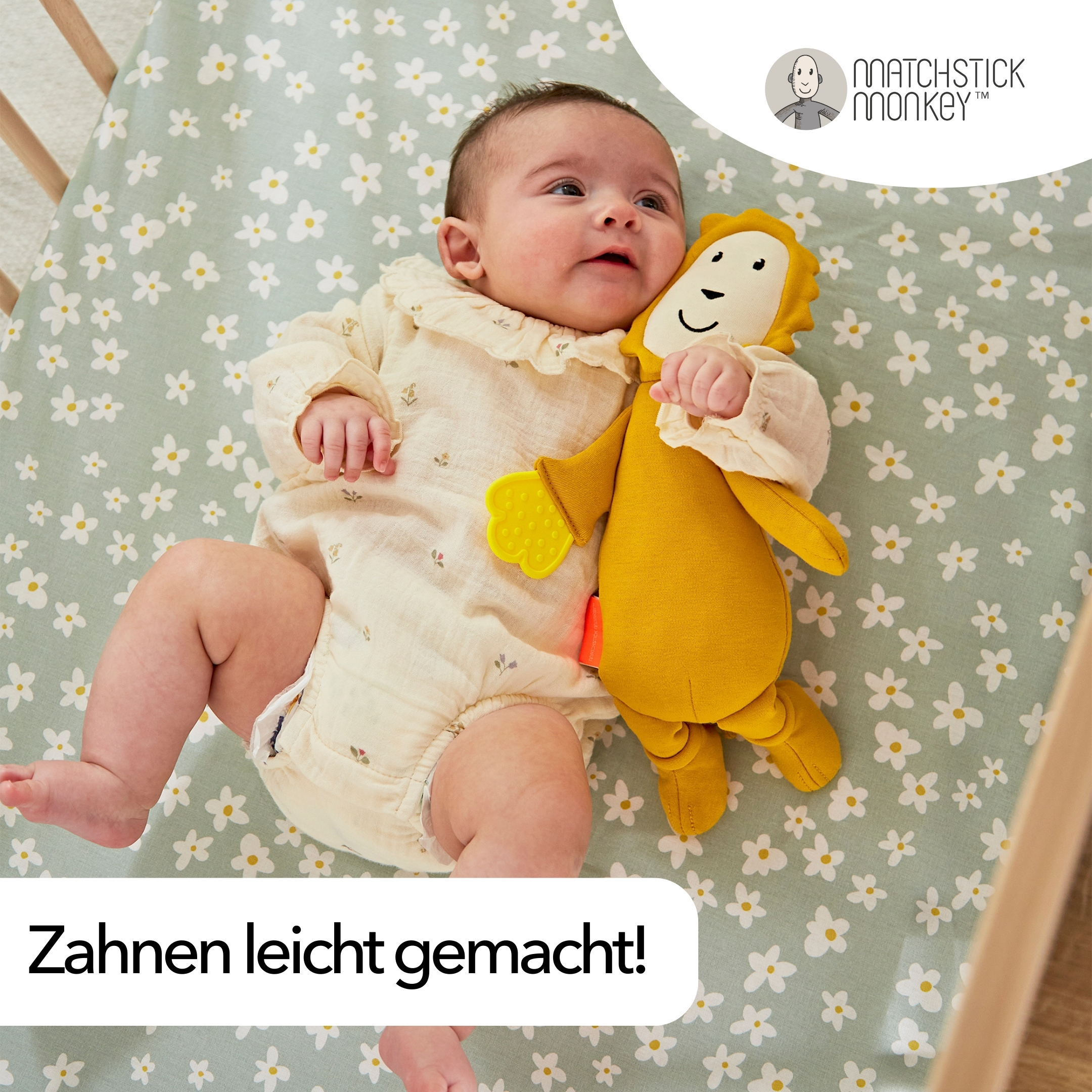 Ein Baby liegt auf einem Blumenlaken und hält einen Löwen-Beißring. Text 'Zahnen leicht gemacht!'.