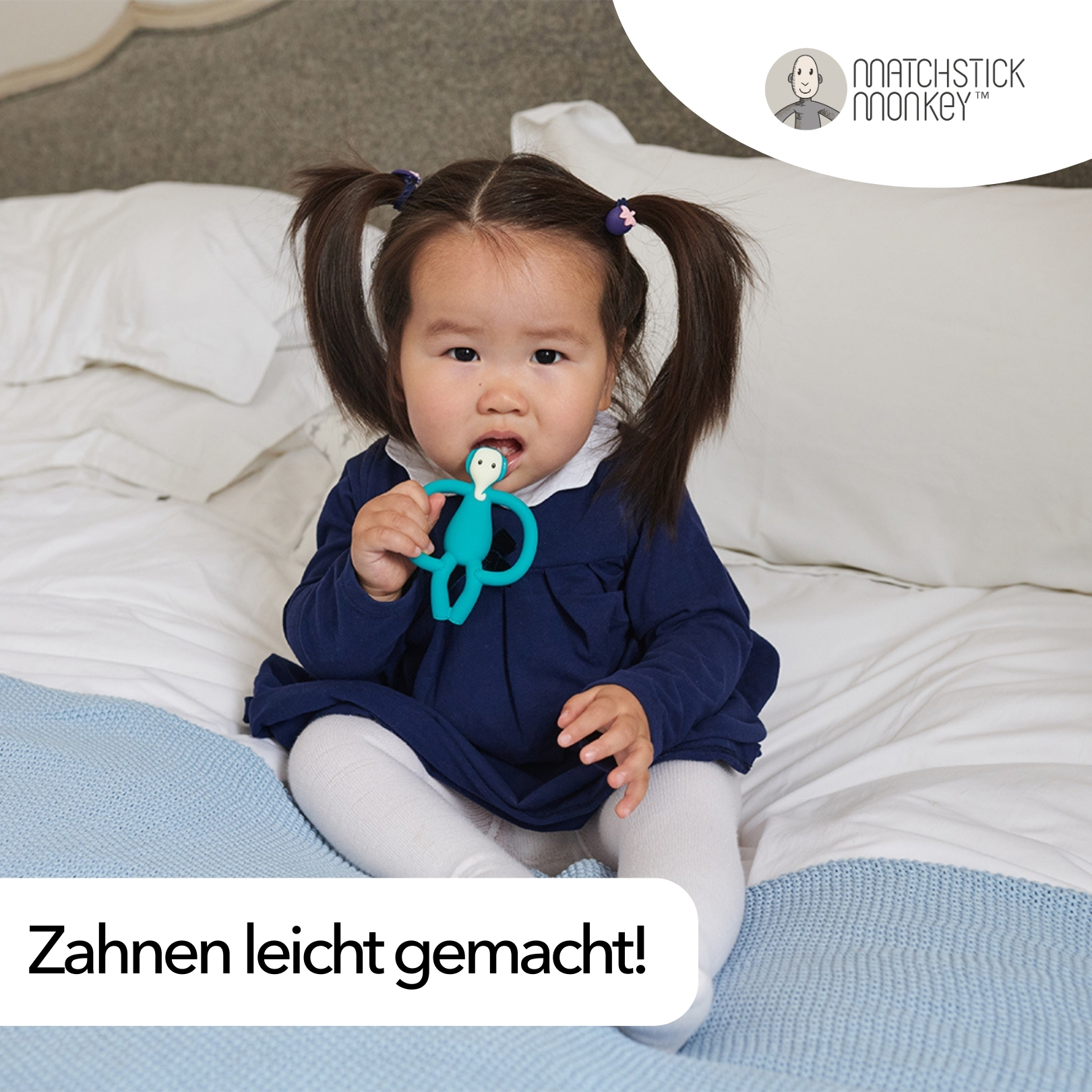 Ein Baby mit Zöpfen sitzt auf einem Bett und hält einen türkisfarbenen Affenbeißring. Text: 'Zahnen leicht gemacht!'