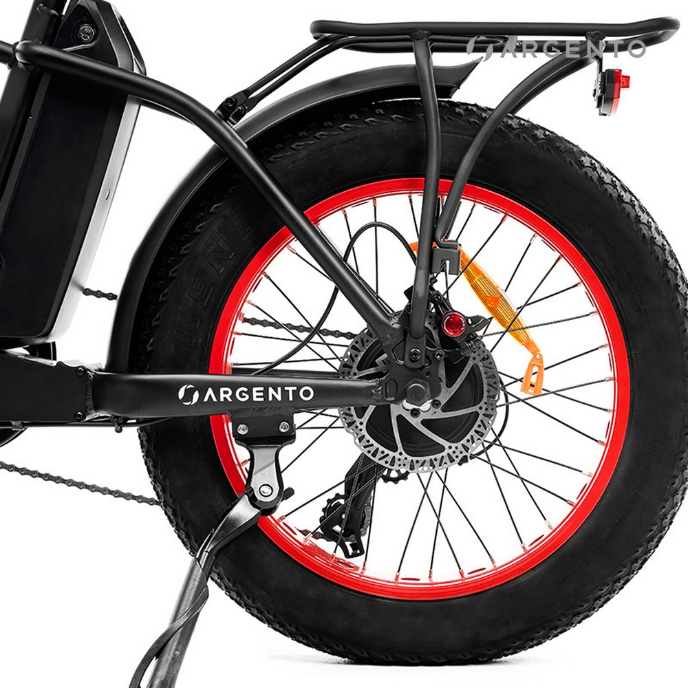 Primo piano della ruota posteriore di una bici elettrica nera e rossa, sfondo bianco.