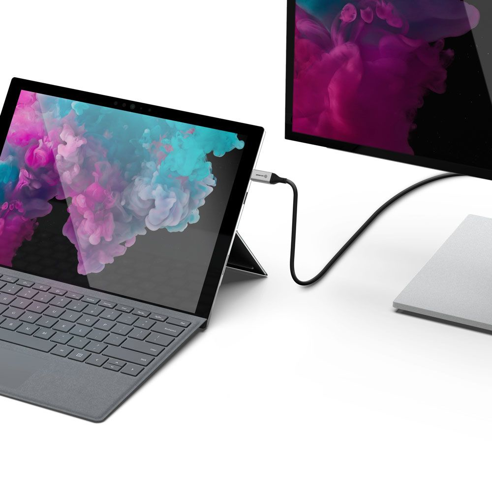 Un ordinateur portable est connecté à un moniteur avec un câble noir. L'écran affiche un arrière-plan coloré.