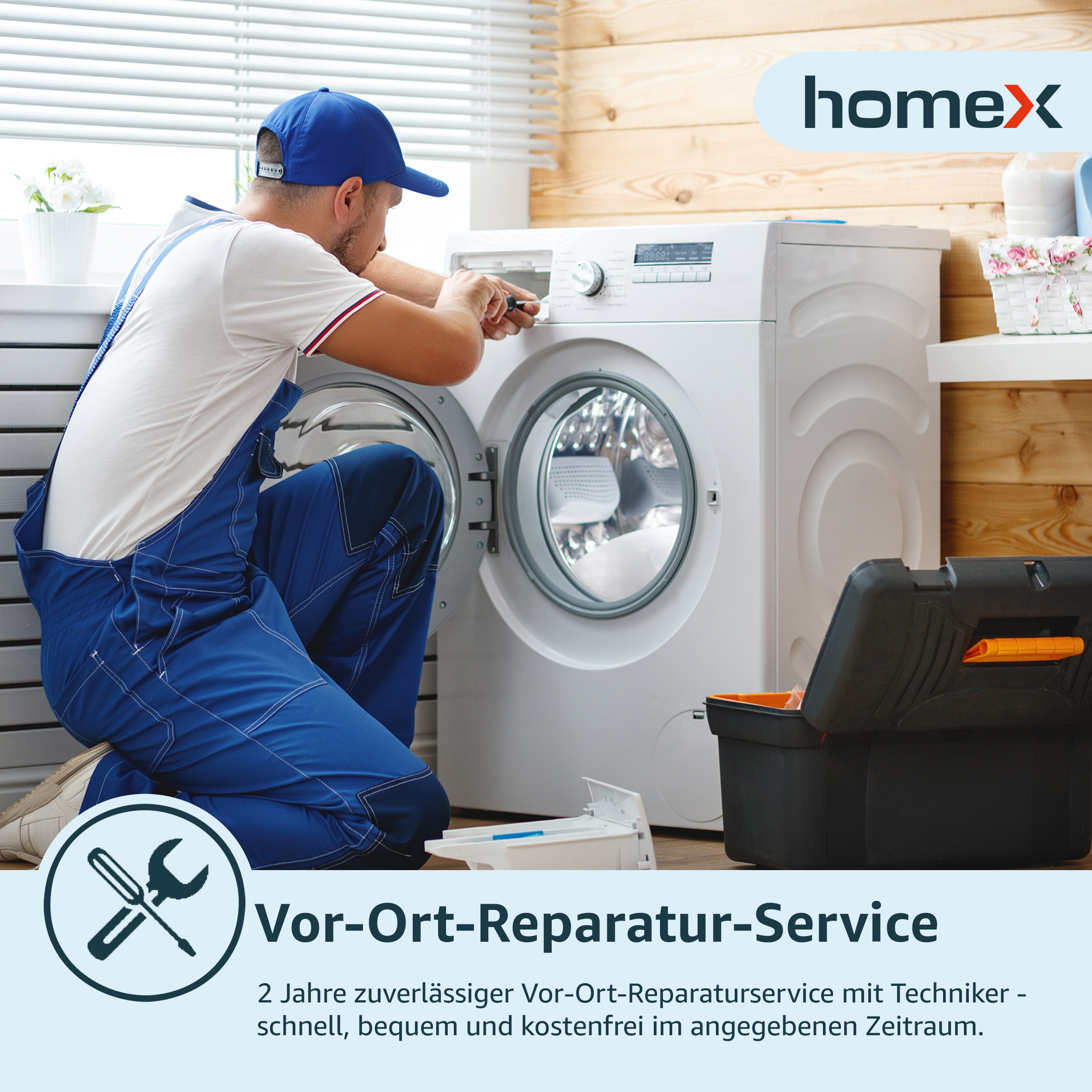 Ein Reparateur in blauen Overalls repariert eine Waschmaschine. Eine Werkzeugkiste steht auf dem Boden.