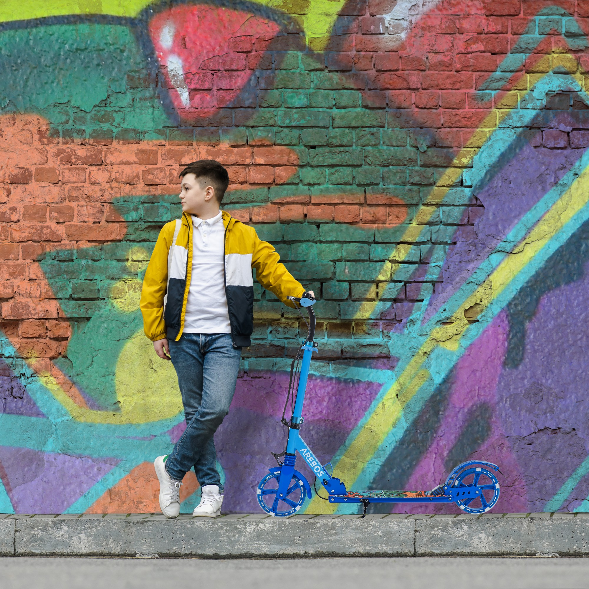 Ein Junge lehnt an einem blauen Roller an einer mit Graffiti bedeckten Ziegelmauer.