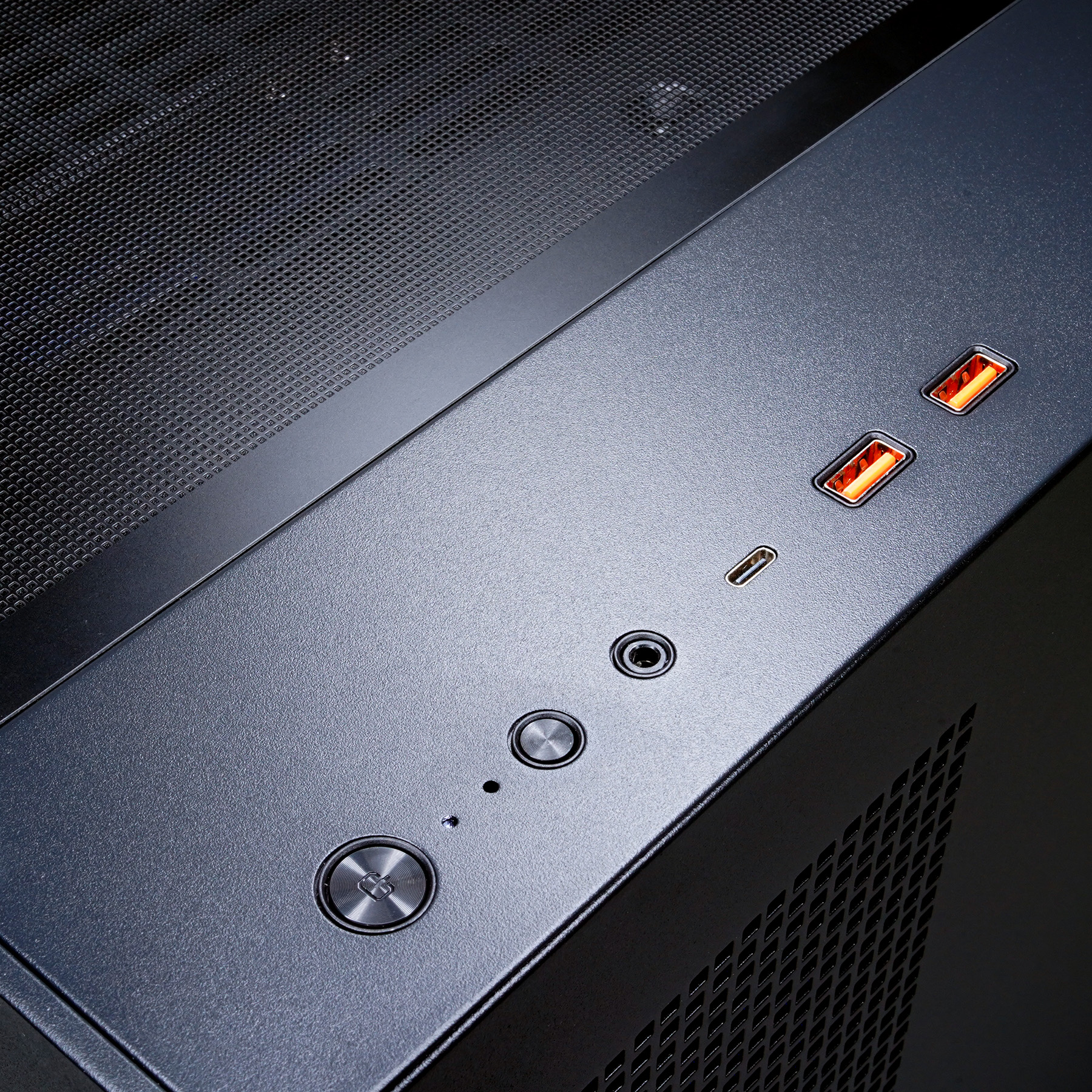 Primo piano della parte superiore di un case per computer nero. Pulsante di accensione, porte USB e jack audio visibili.