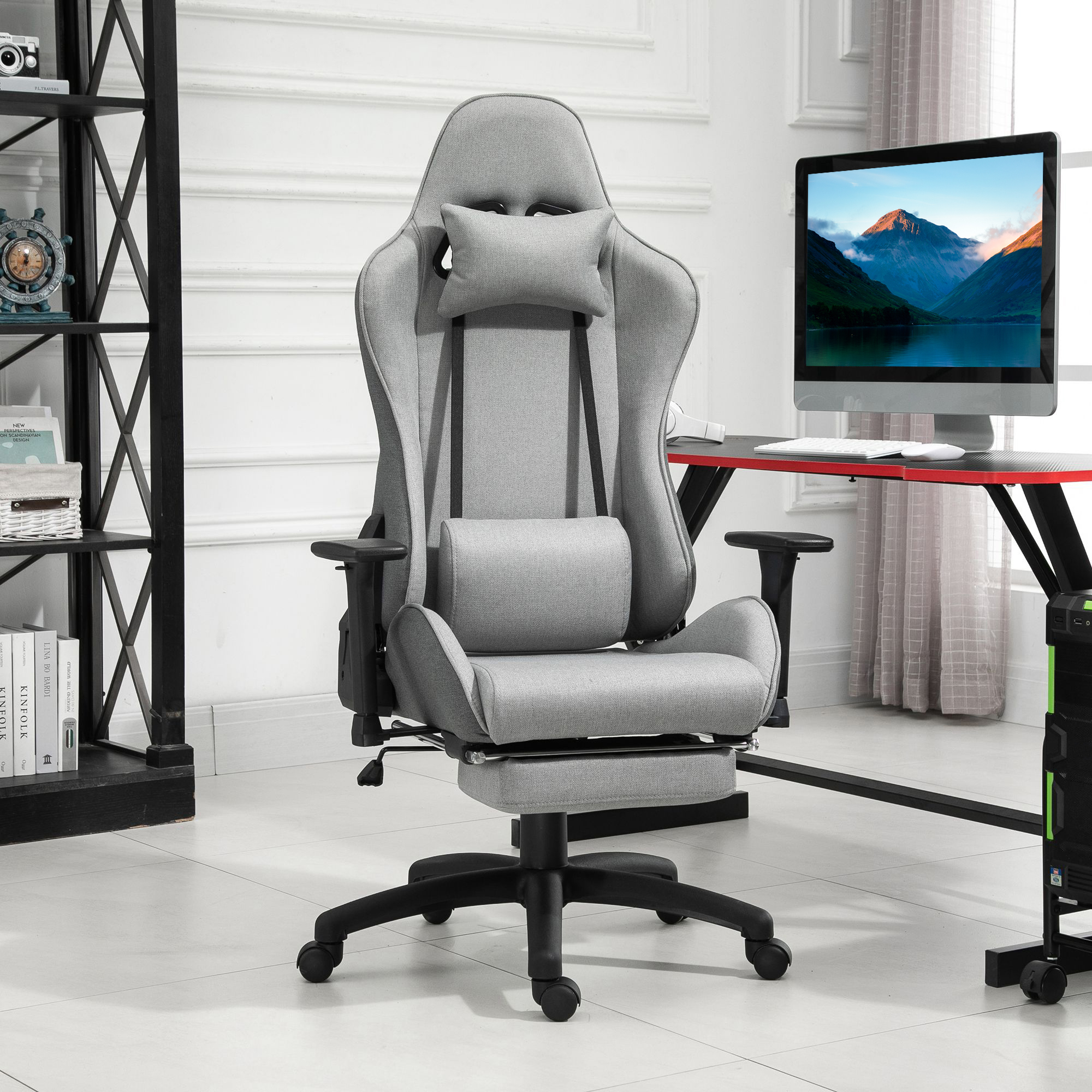 Grauer Gaming-Stuhl mit Fußstütze. In einem Raum mit Computer und Fenster.