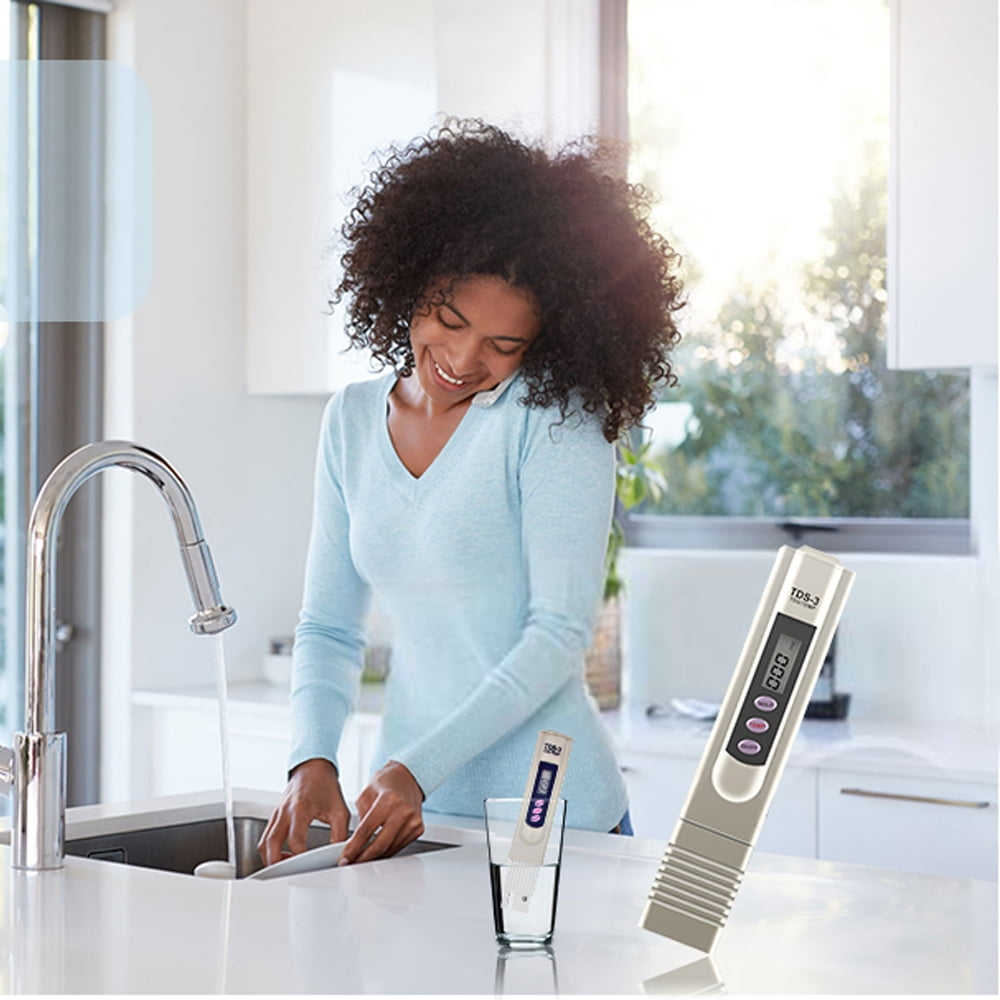 Frau, die einen Wasserqualitätsprüfer verwendet, in der Nähe eines Waschbeckens und eines Wasserglases.