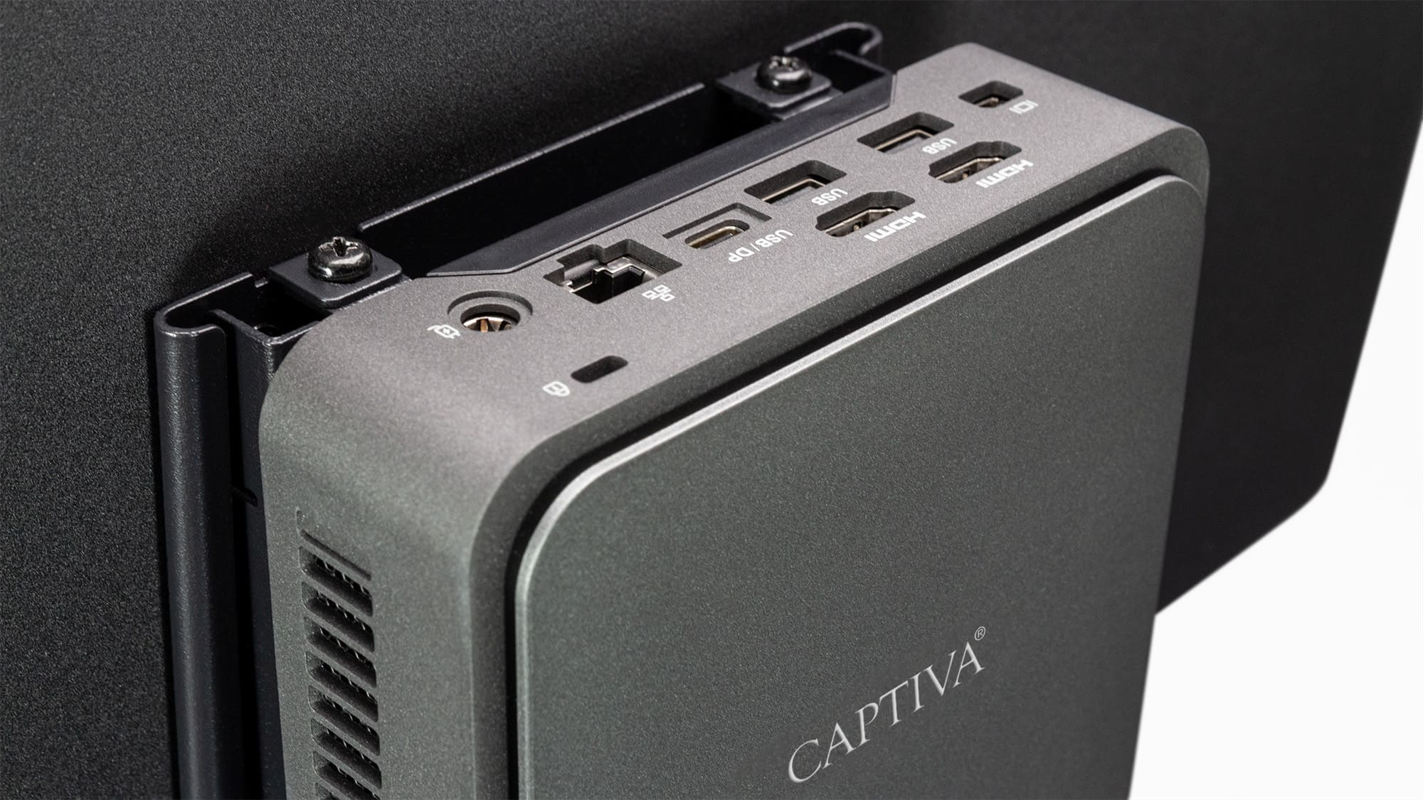 Szary komputer Captiva na czarnej ramie. Posiada porty takie jak USB i HDMI.