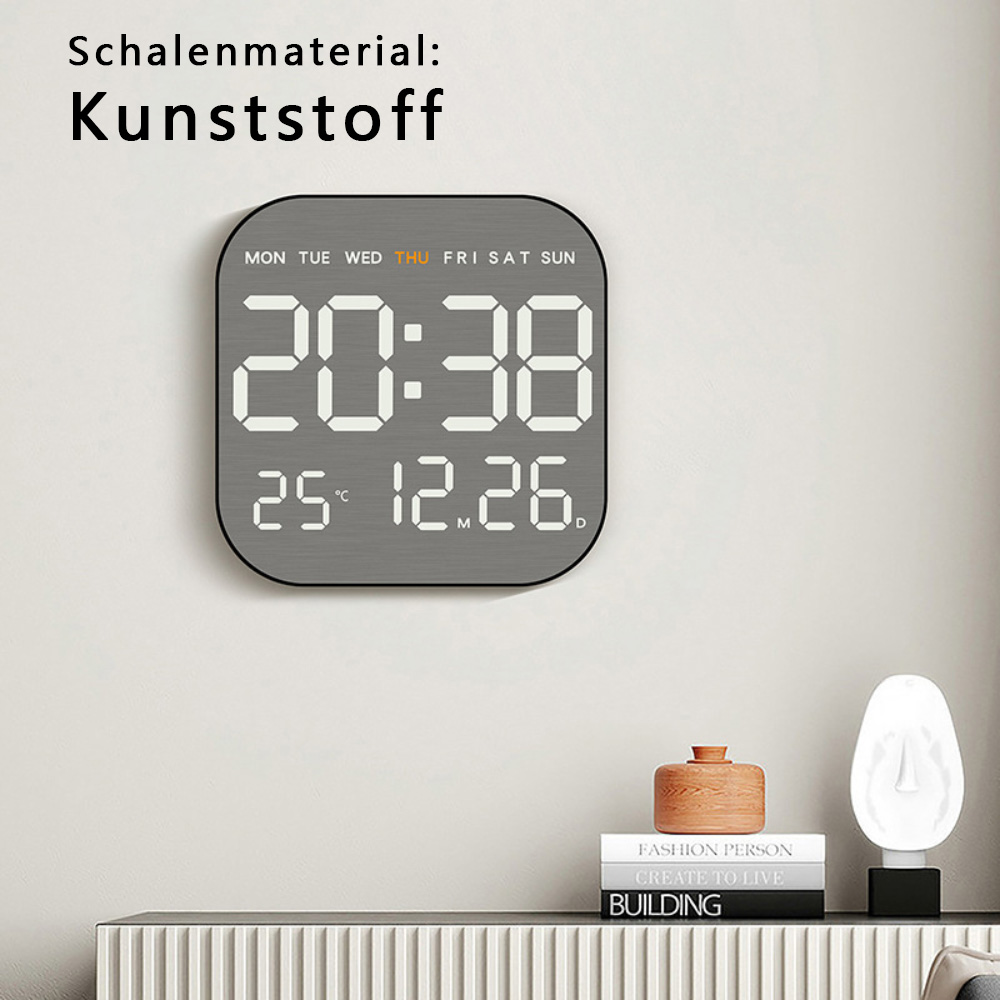 Digitaluhr zeigt 20:38, Datum, Tag. Grauer Rahmen, weiße Ziffern, an einer weißen Wand mit Dekor.