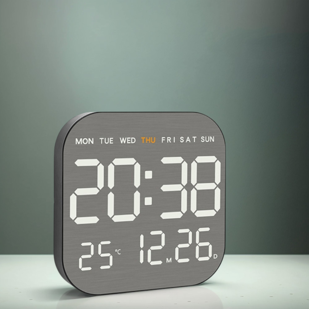 Digitaluhr zeigt 20:38 und das Datum. Die Uhr hat einen grauen Rahmen und weiße Ziffern an einer Wand.