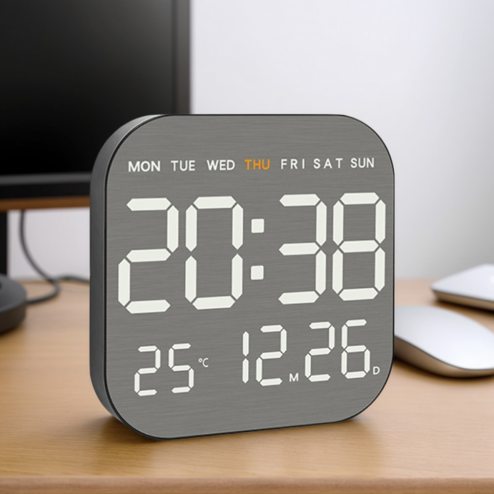 Eine Digitaluhr zeigt 20:38, 25°C und 12.26 an. Sie steht auf einem Holzschreibtisch.