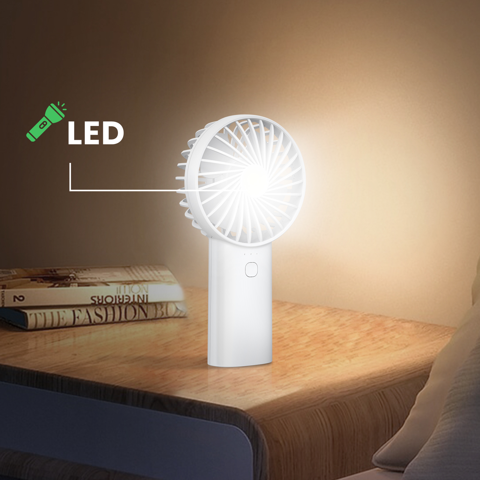 Weißer Handventilator mit Griff auf einem Nachttisch aus Holz, neben Büchern. LED-Licht scheint.