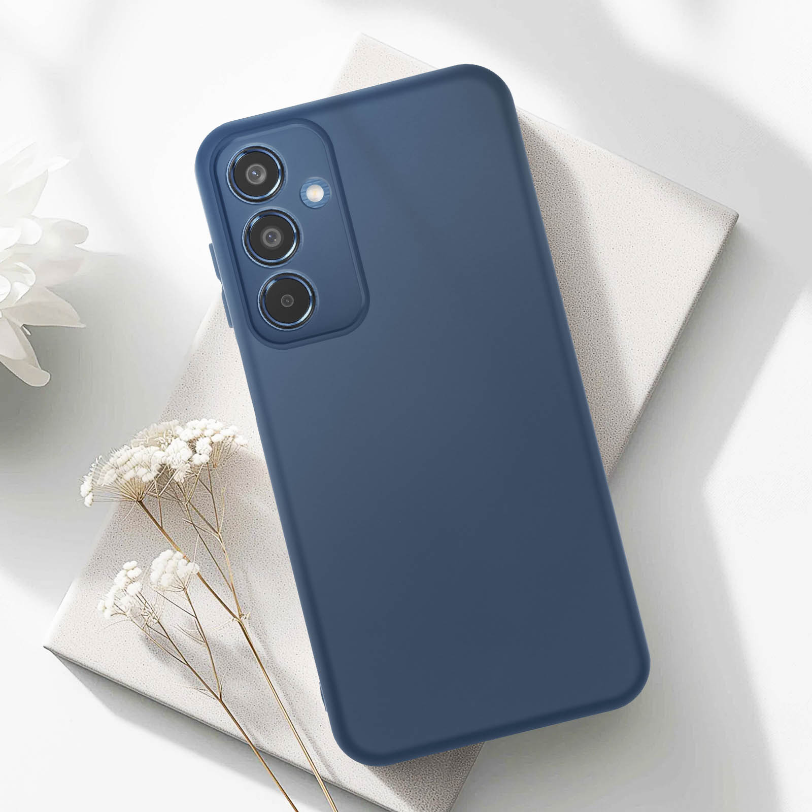 Una custodia blu per telefono con tre fotocamere su una superficie bianca con una pianta sopra.