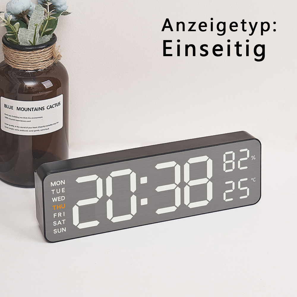 Digitaluhr mit Zeit- und Temperaturanzeige auf weißem Tisch.
