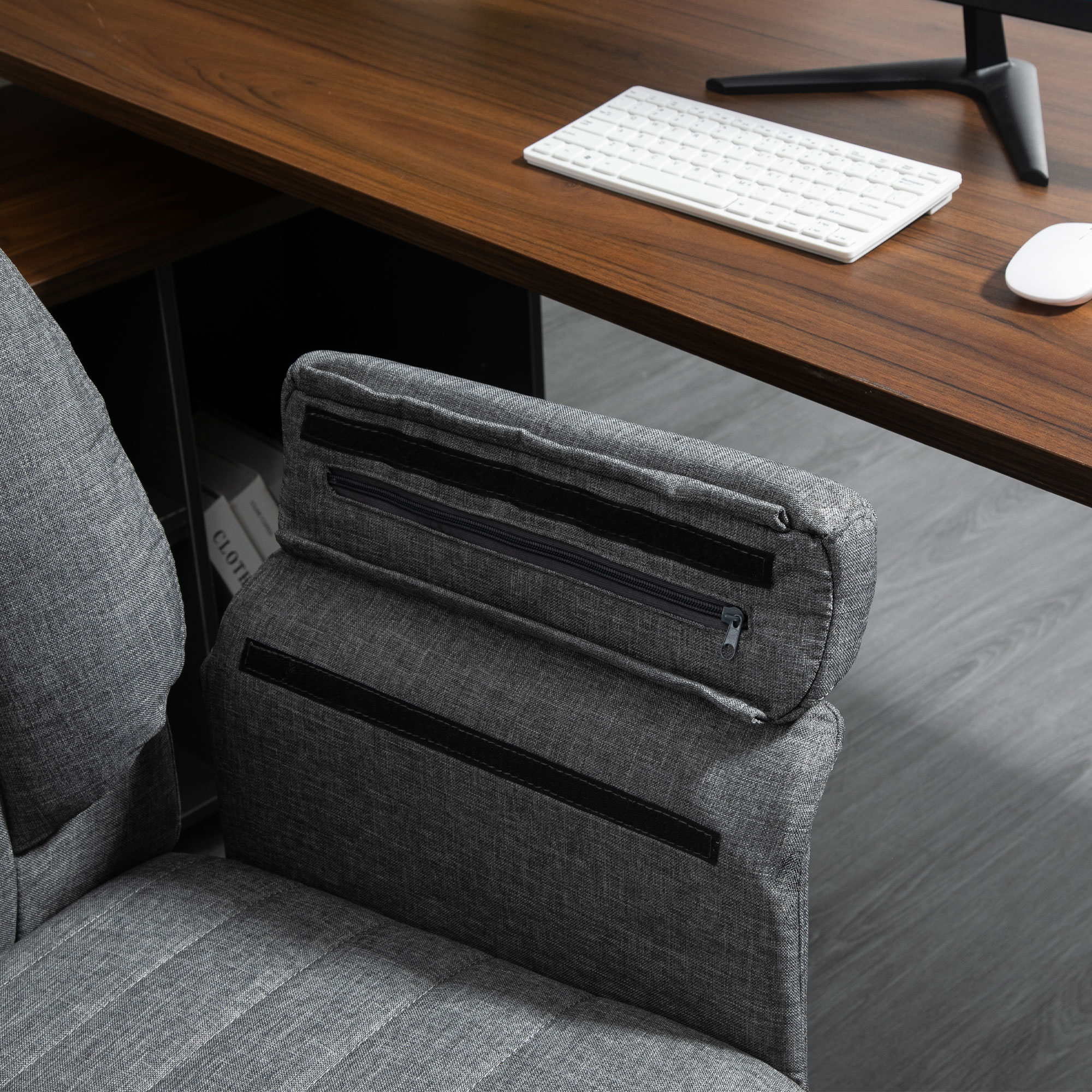 Nahaufnahme eines grauen Bürostuhls mit Schreibtisch, Tastatur und Maus im Hintergrund.