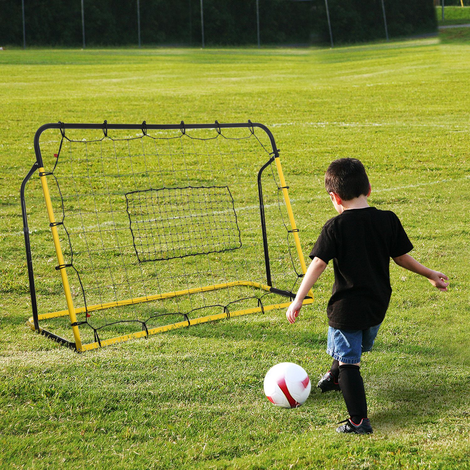 Junge tritt einen Fußball in Richtung eines gelb-schwarzen Tors auf einem Rasen.