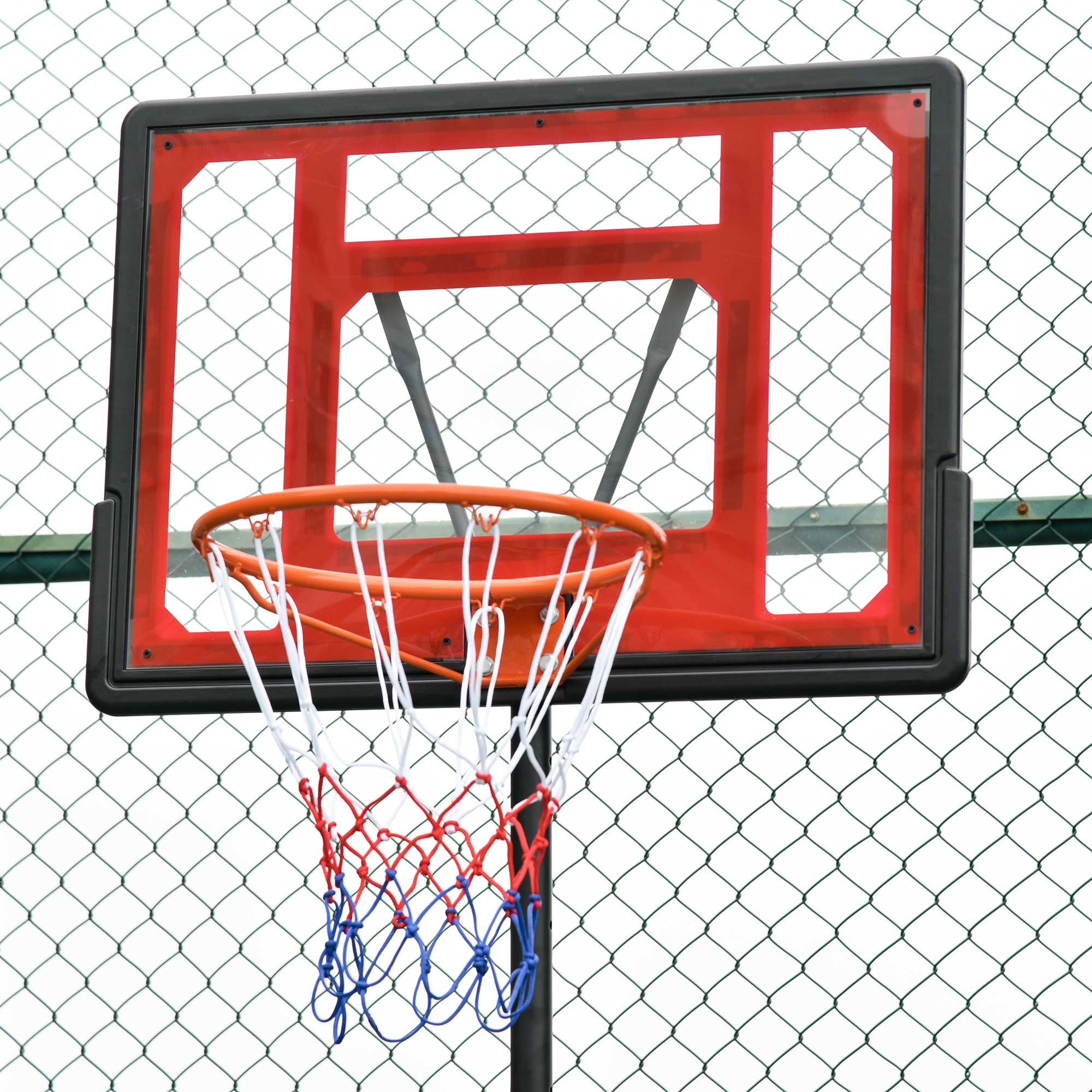 Nahaufnahme des Basketballkorbs. Rote Rückwand, orangefarbener Ring und weißes, rotes und blaues Netz.