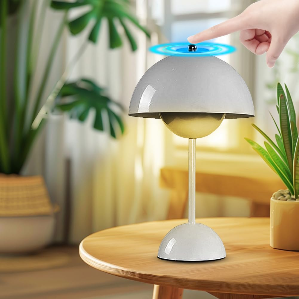 Weiße Schreibtischlampe, berührungsgesteuert, auf einem Holztisch mit Pflanzen und einer Hand, die die Oberseite berührt.