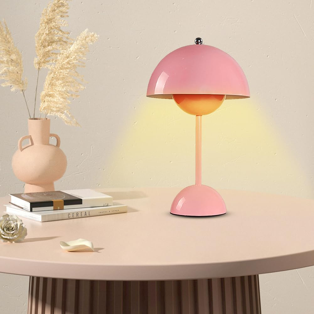 Rosa Schreibtischlampe mit Kuppel, auf rundem Tisch mit Büchern und Vase, vor hellem Hintergrund.