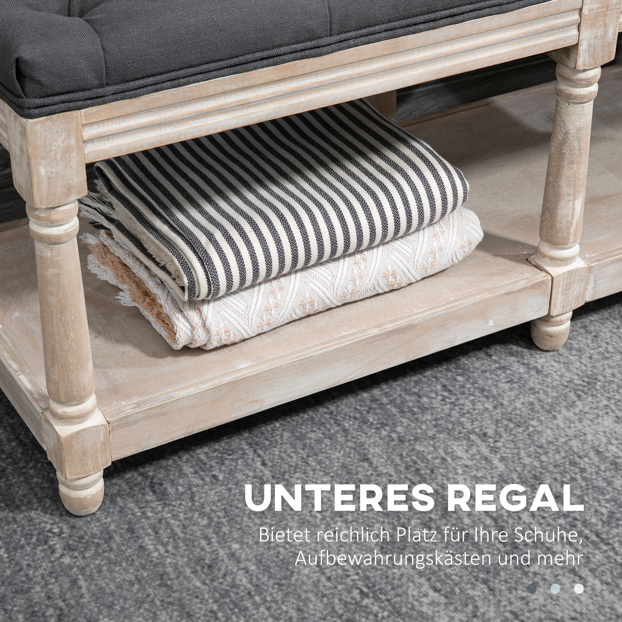 Holzbank mit grauem Kissen, unteres Regal mit gefalteten Decken, grauer Teppich.