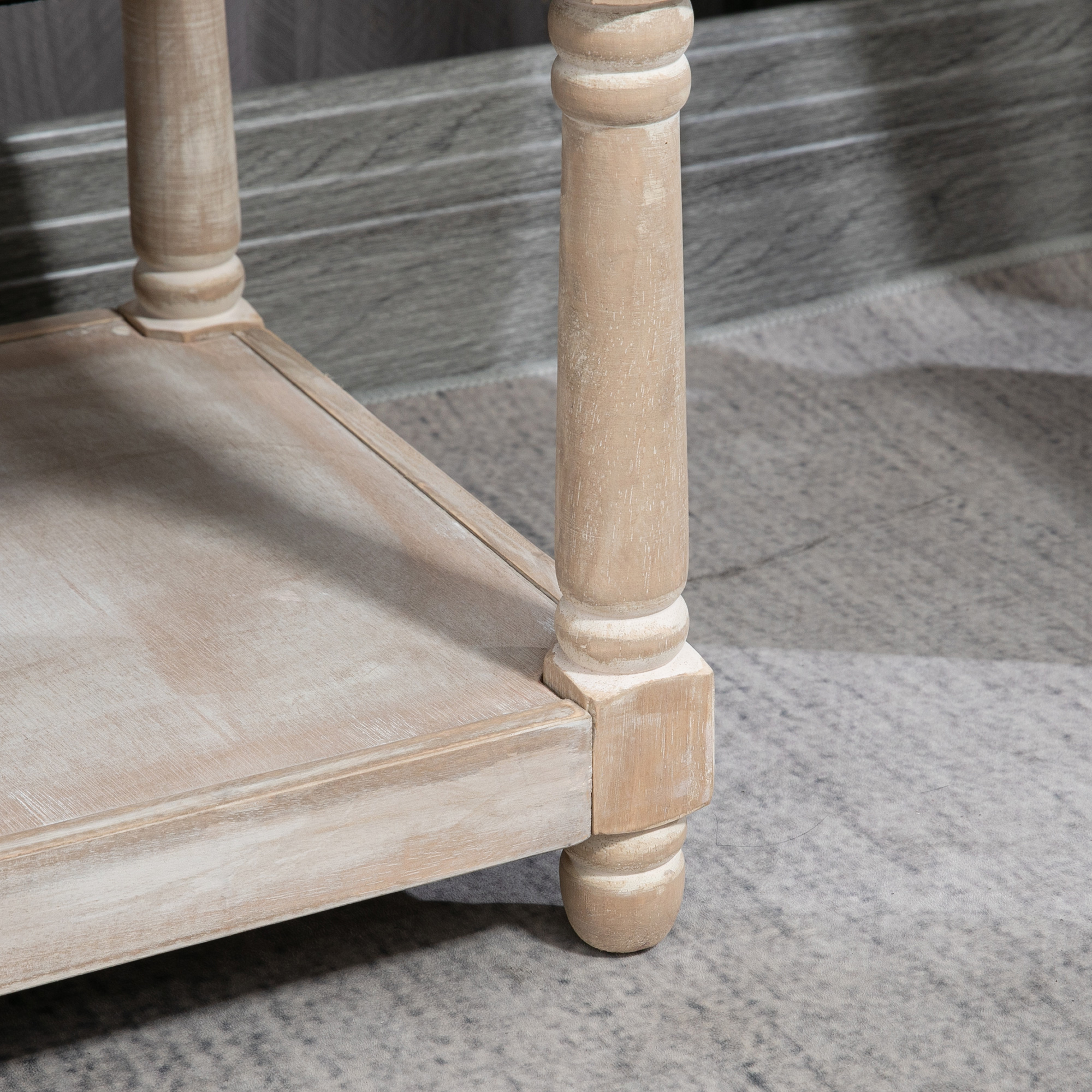 Nahaufnahme von hellem Holz-Tischbein und Regal auf grauem Teppich.