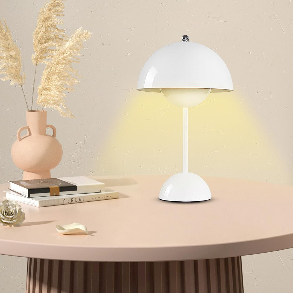 Eine weiße Lampe auf einem rosa Tisch, eine Vase mit Pampasgras, Bücher und eine kleine Schale sind vorhanden.