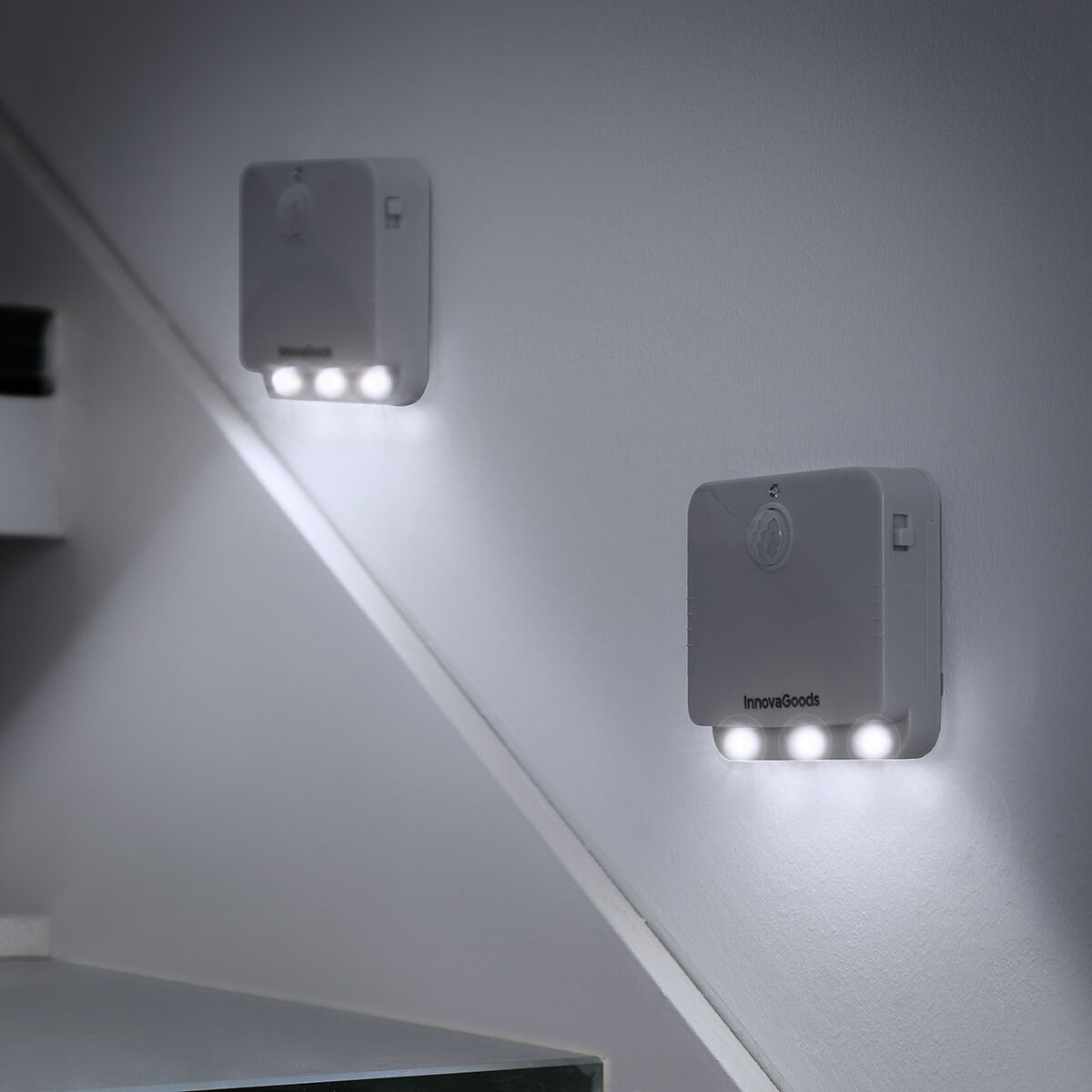 Due luci InnovaGoods su un muro, che illuminano una scala. Le luci sono bianche e quadrate.
