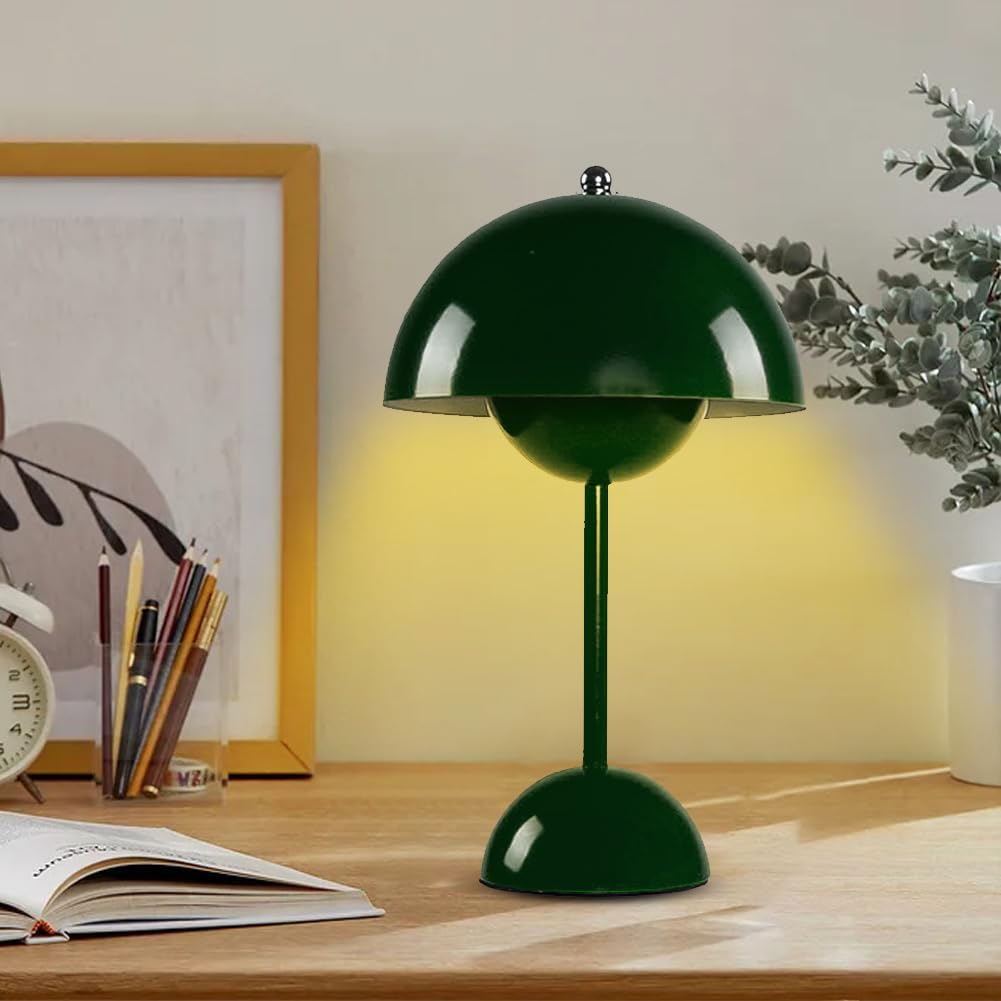 Eine grüne Tischlampe auf einem Schreibtisch. Ein Buch, Bleistifte und ein Bilderrahmen stehen daneben.