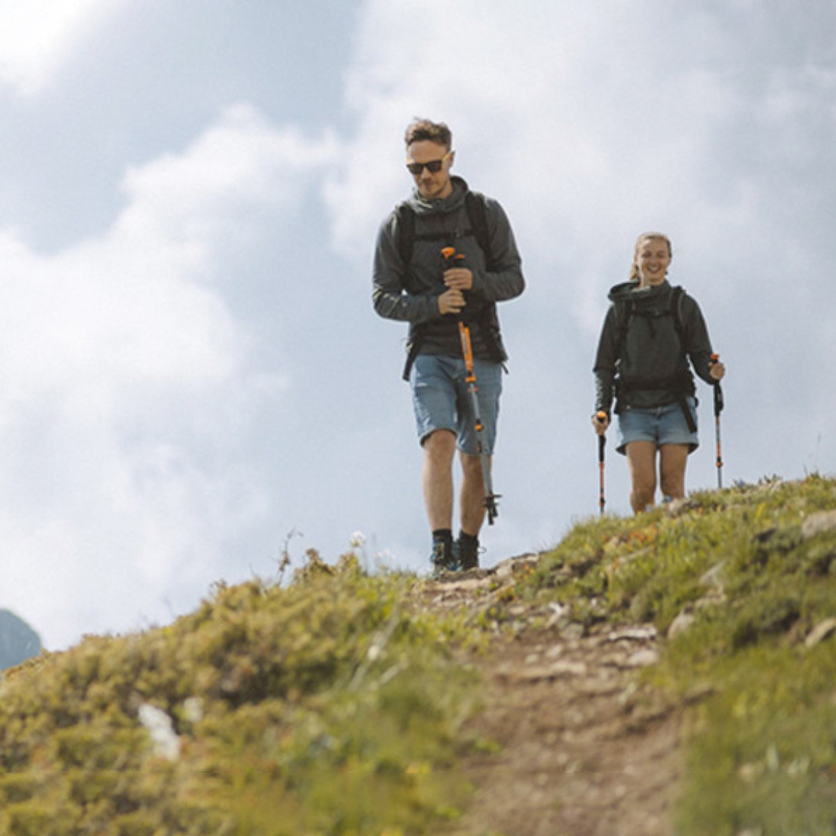 Dwóch turystów z kijkami trekkingowymi idących górskim szlakiem.