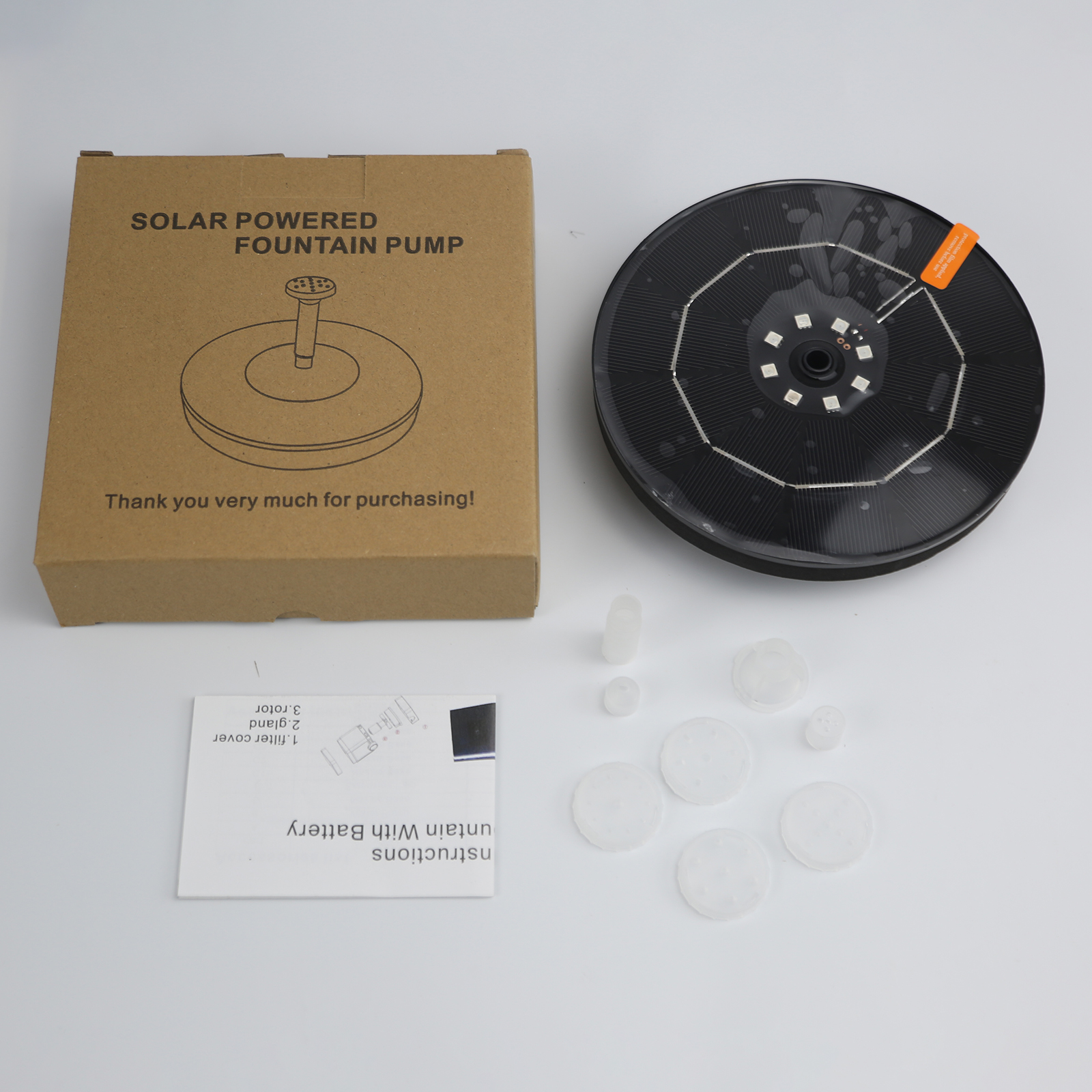Elementy fontanny zasilanej energią słoneczną: pudełko, fontanna i akcesoria na białej powierzchni.