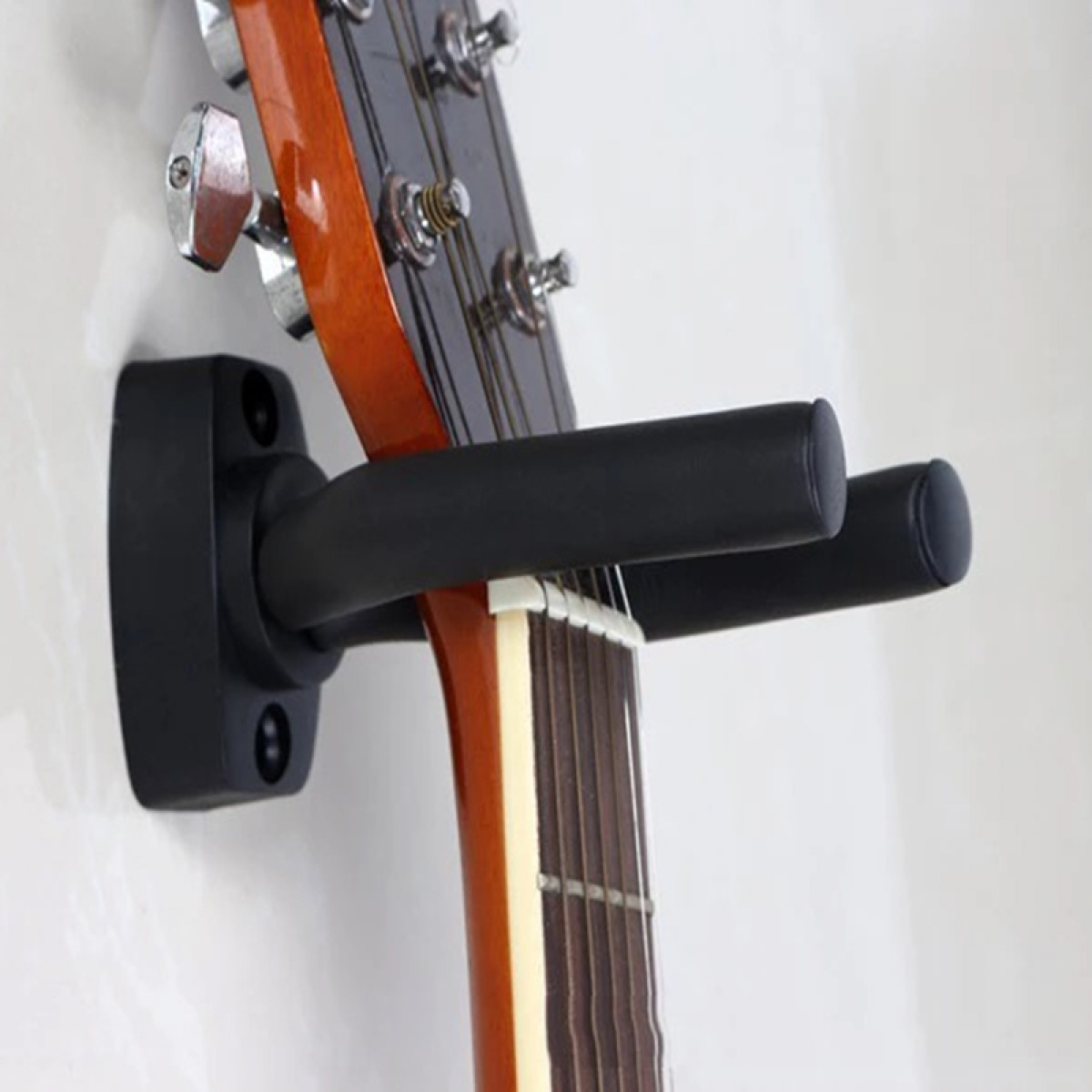 Support de guitare noir monté sur un mur, soutenant le manche d'une guitare. Fond blanc.