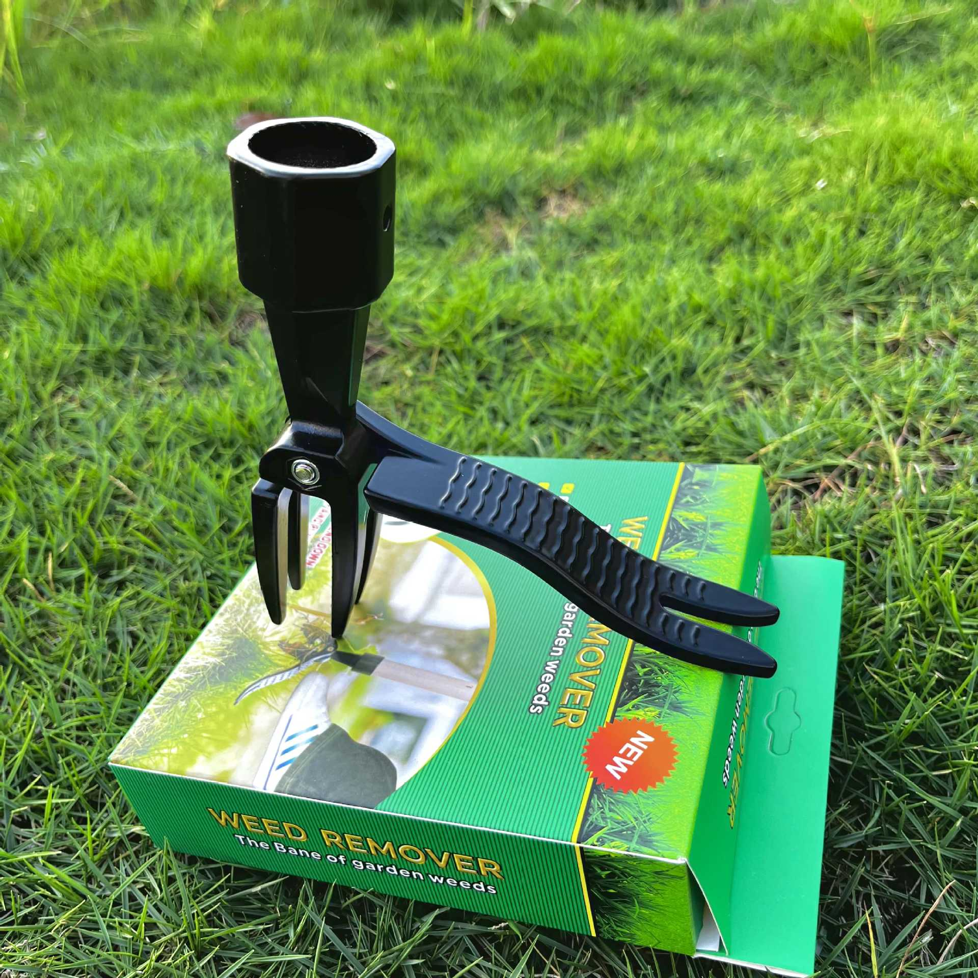Zielone pudełko zawierające narzędzie do usuwania chwastów z narzędziem na trawie.