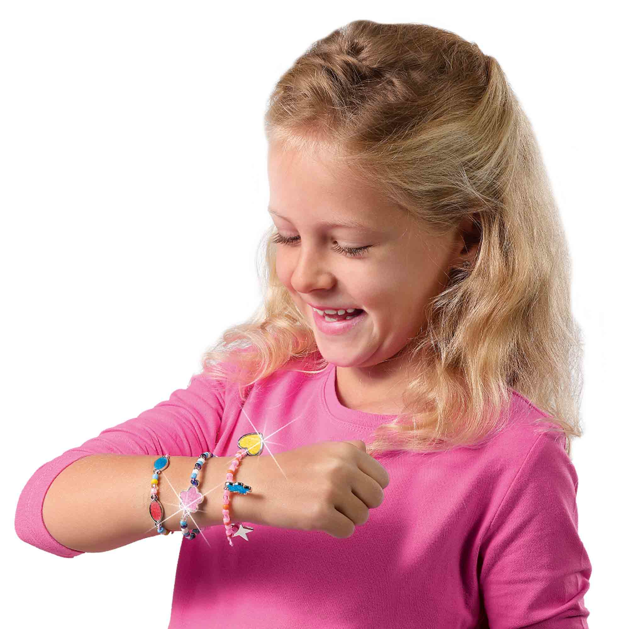 Una ragazza sorride, indossa braccialetti al polso. I braccialetti sono colorati.