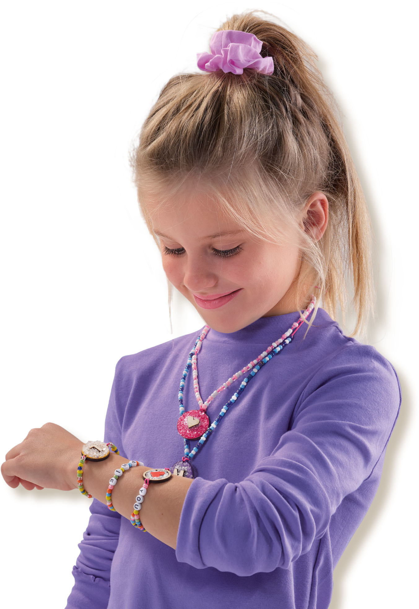 Mädchen mit Perlenkette. Sie trägt eine Halskette, ein Armband und prüft ein weiteres Armband.